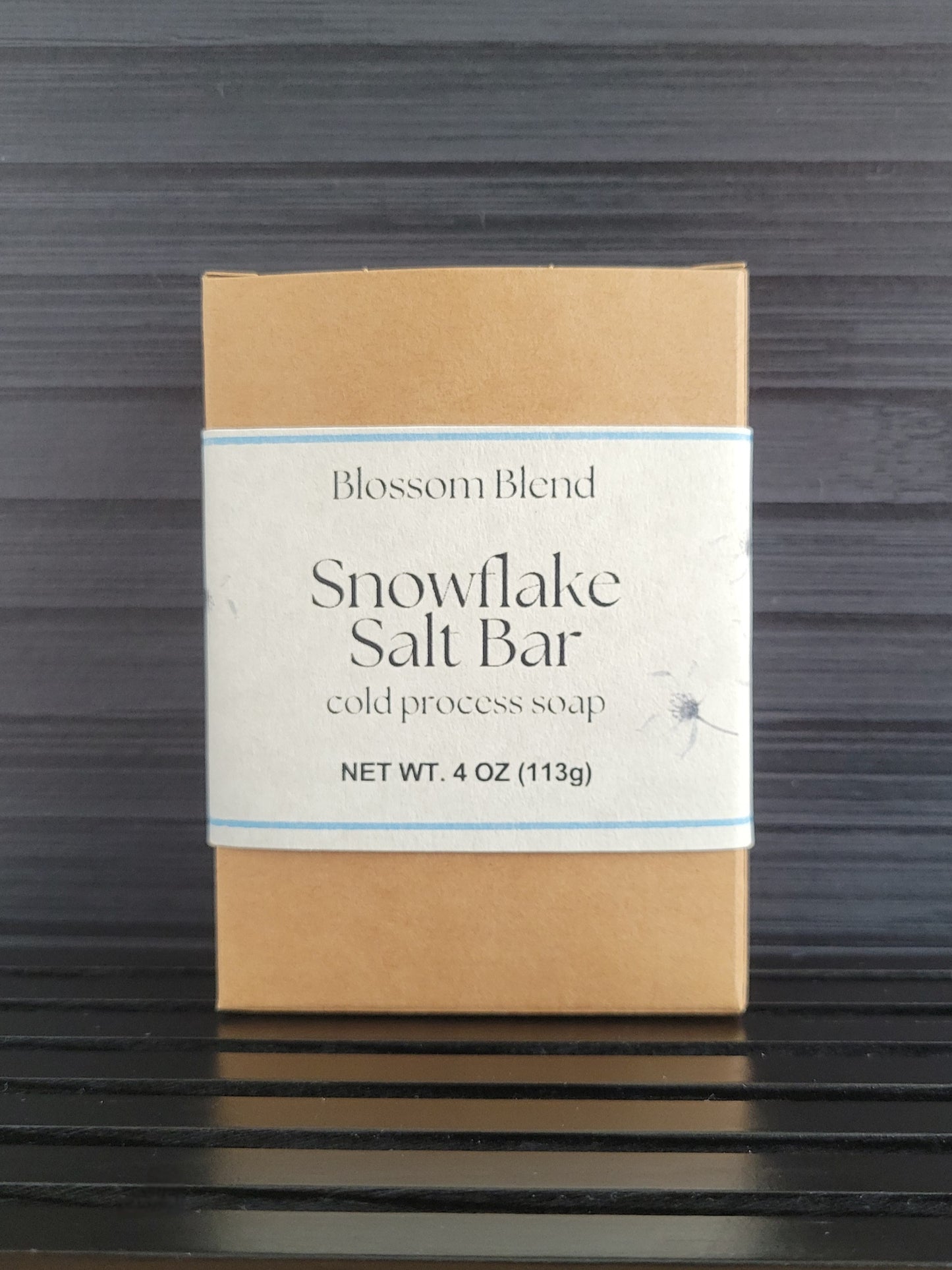 Blossom Blend Snowflake Salt Bar soap packaging on a dark wooden surface