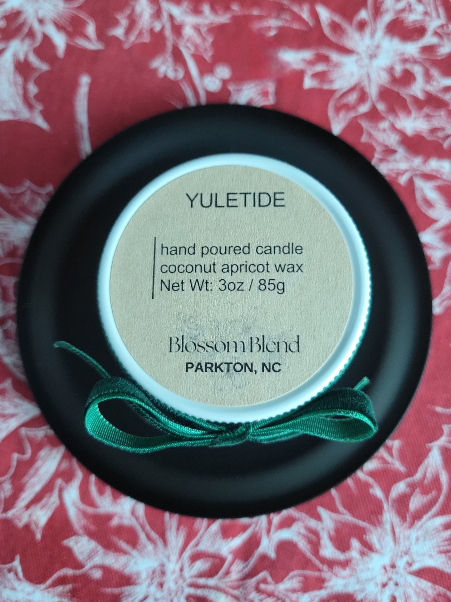 Yuletide candle with label on a red and white floral background