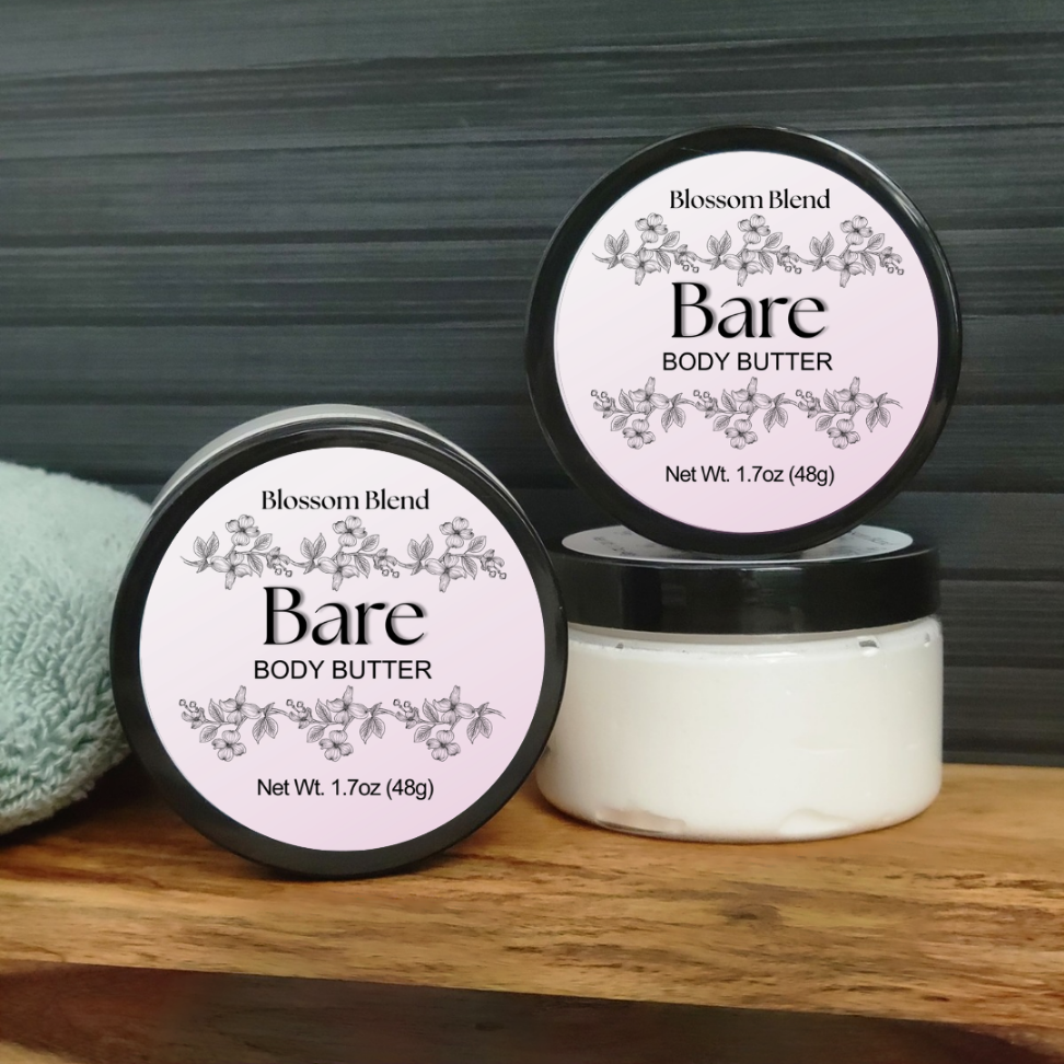 Two jars of Blossom Blend Bare Body Butter on a wooden surface with a dark background.