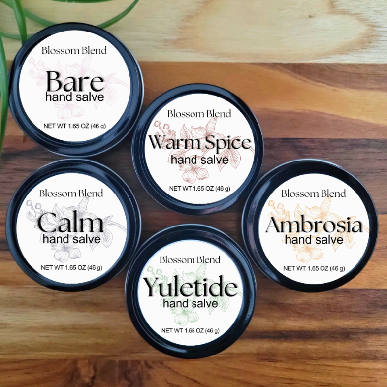 Five containers of Blossom Blend hand salves on a wooden surface.