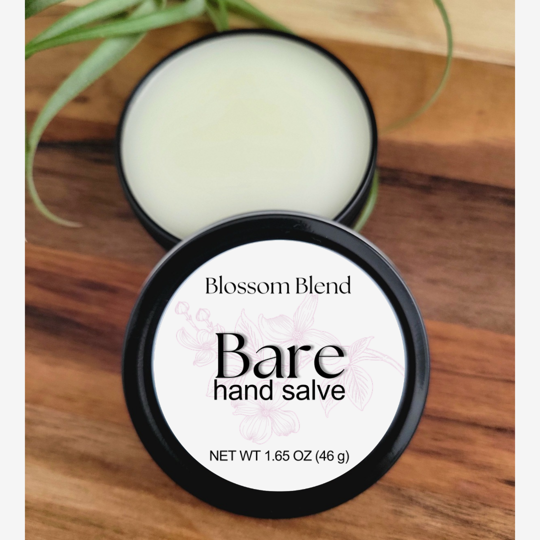 Blossom Blend Bare hand salve container on a wooden surface with a plant in the background