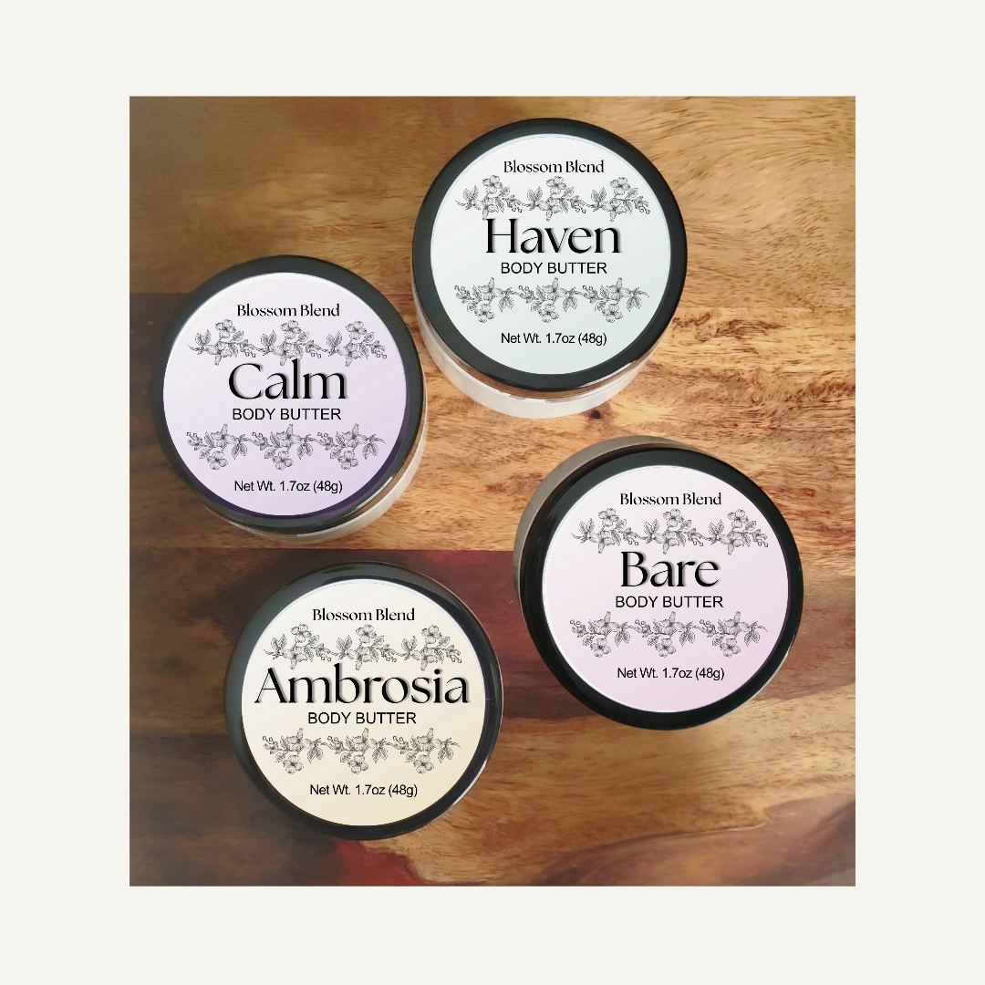 Four containers of Blossom Blend body butter on a wooden surface with labels for Calm, Haven, Ambrosia, and Bare.