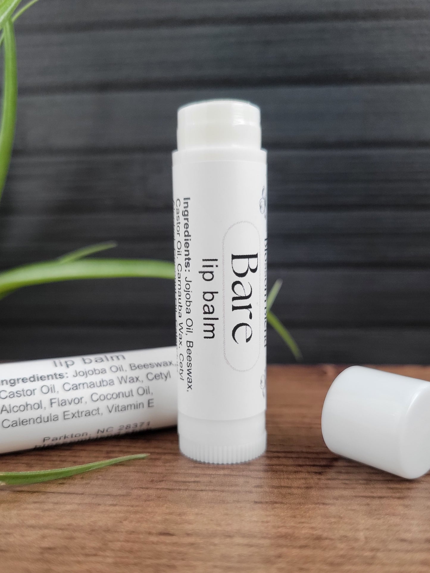 Bare lip balm on a wooden surface with a gray background