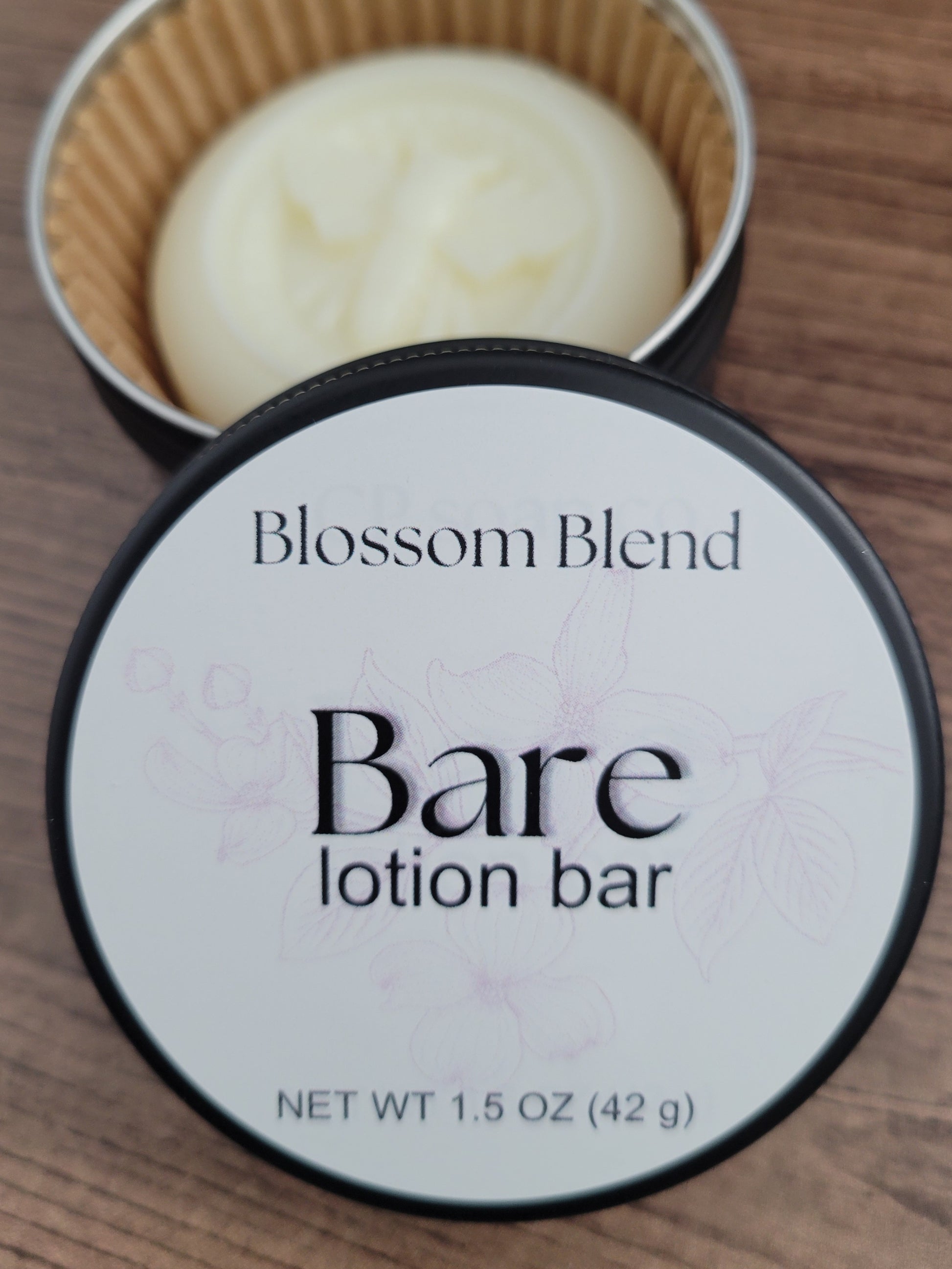 Blossom Blend Bare lotion bar in a container on a wooden surface