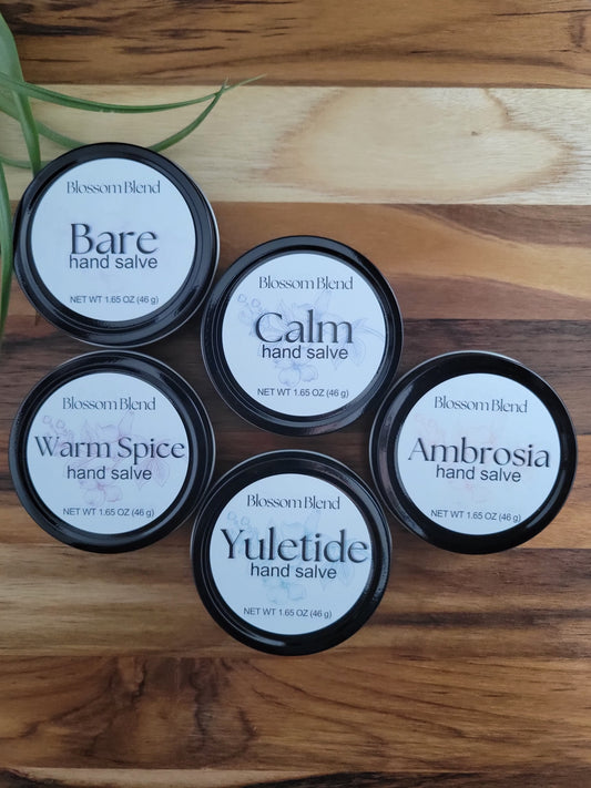 Five containers of Blossom Blend hand salves on a wooden surface