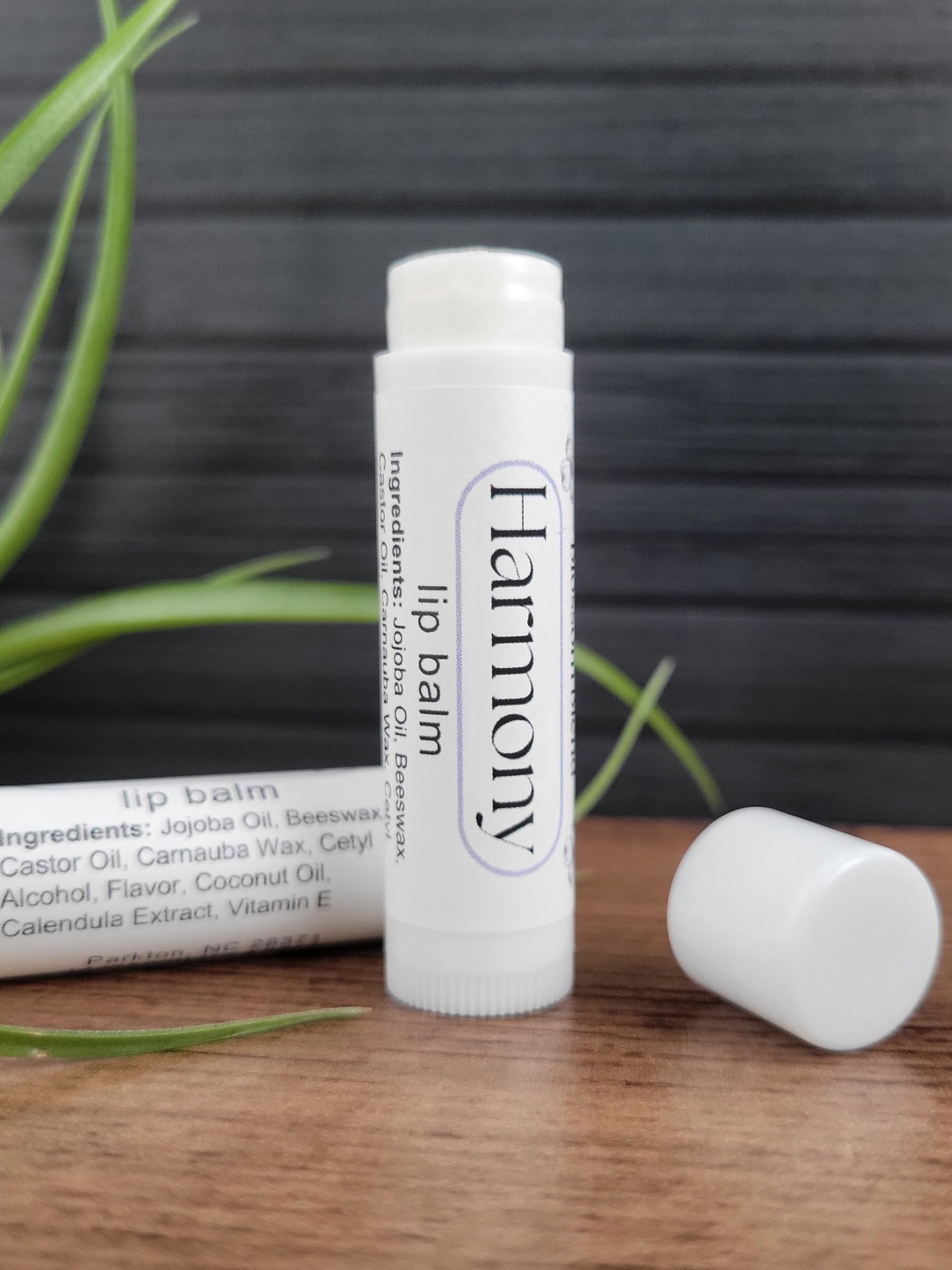 Lip balm labeled 'Harmony' on a wooden surface with a natural background