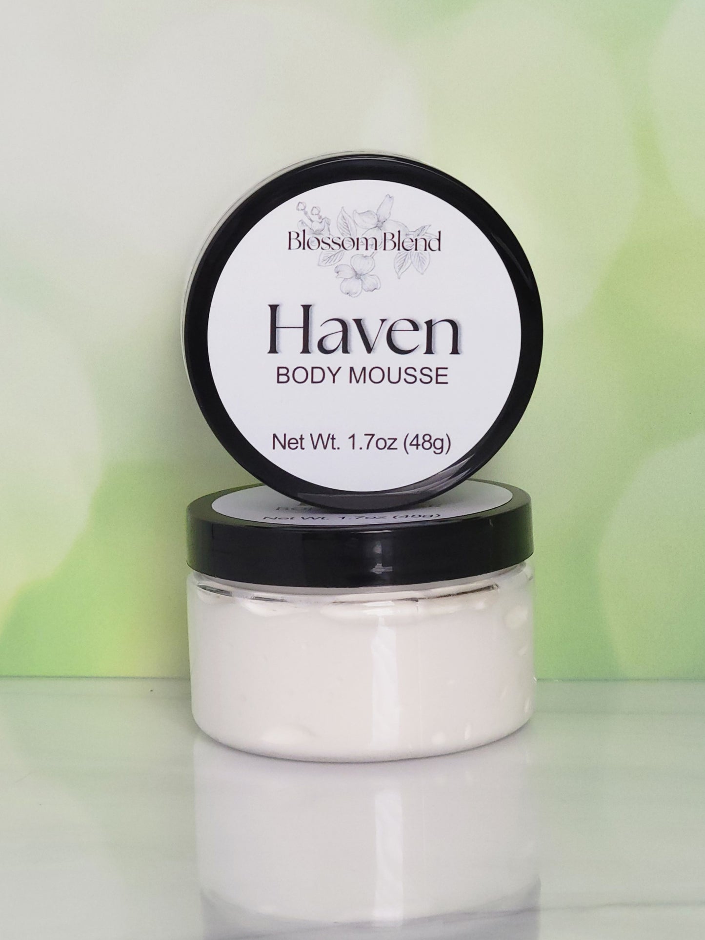 Jar of Haven Body Mousse with a black lid on a light green background