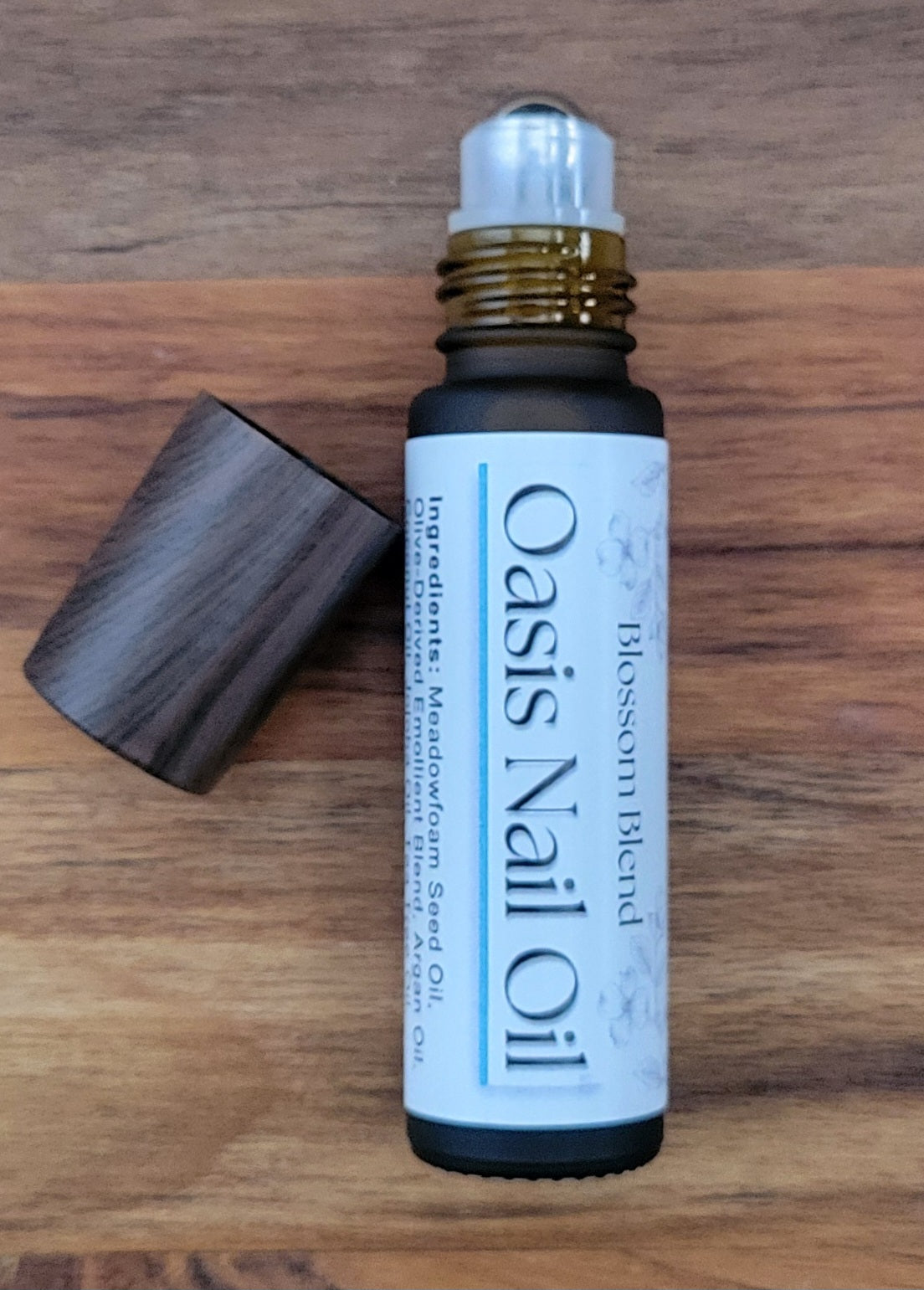 Oasis Nail Oil bottle with wooden applicator on a wooden surface