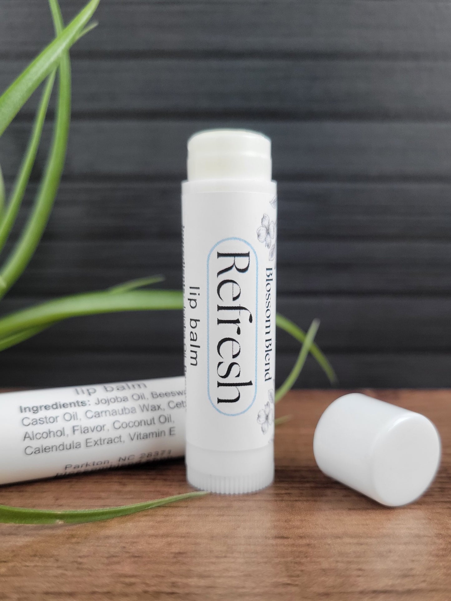 Refresh lip balm on a wooden surface with a gray background