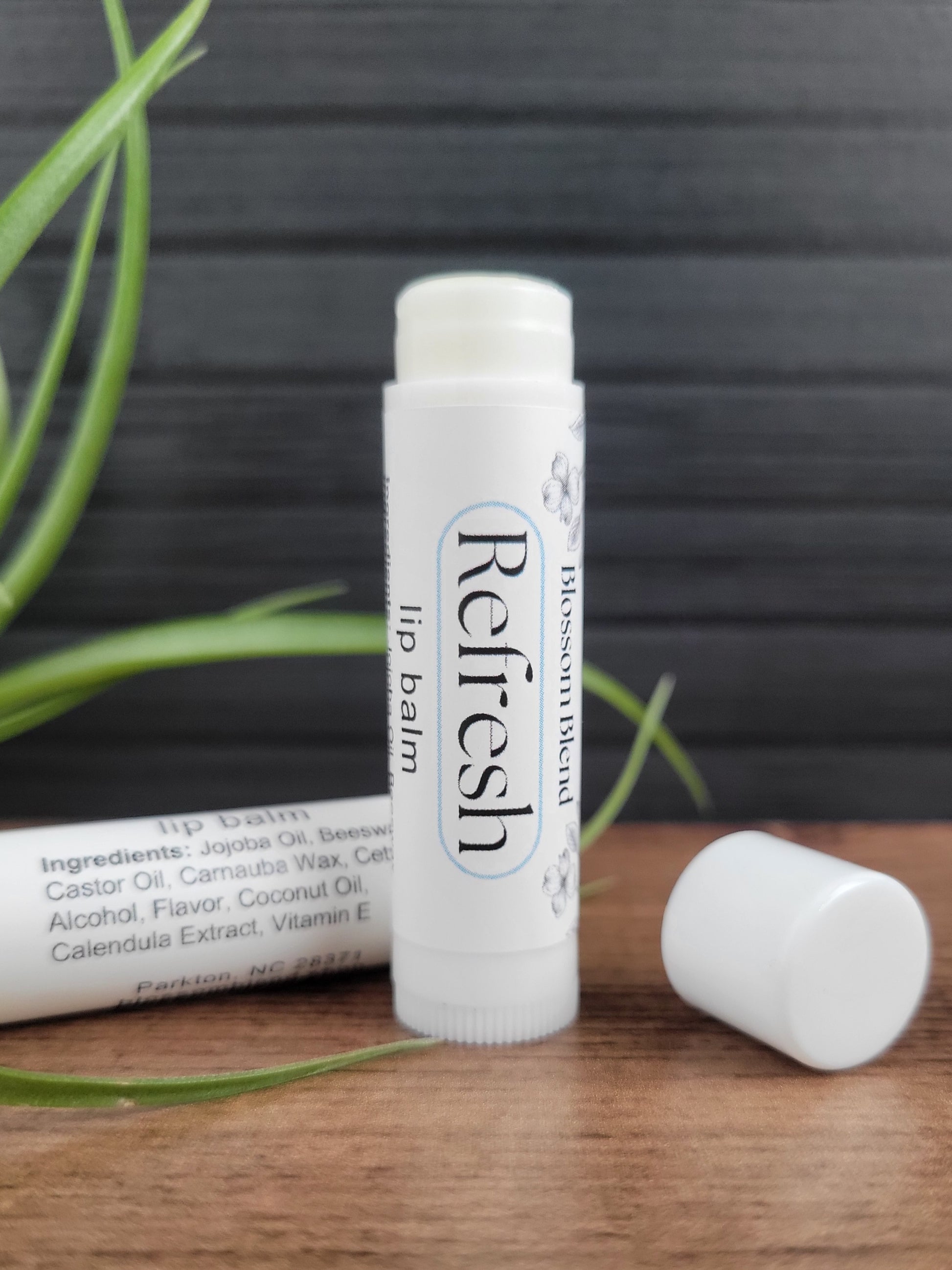 Refresh lip balm on a wooden surface with a gray background
