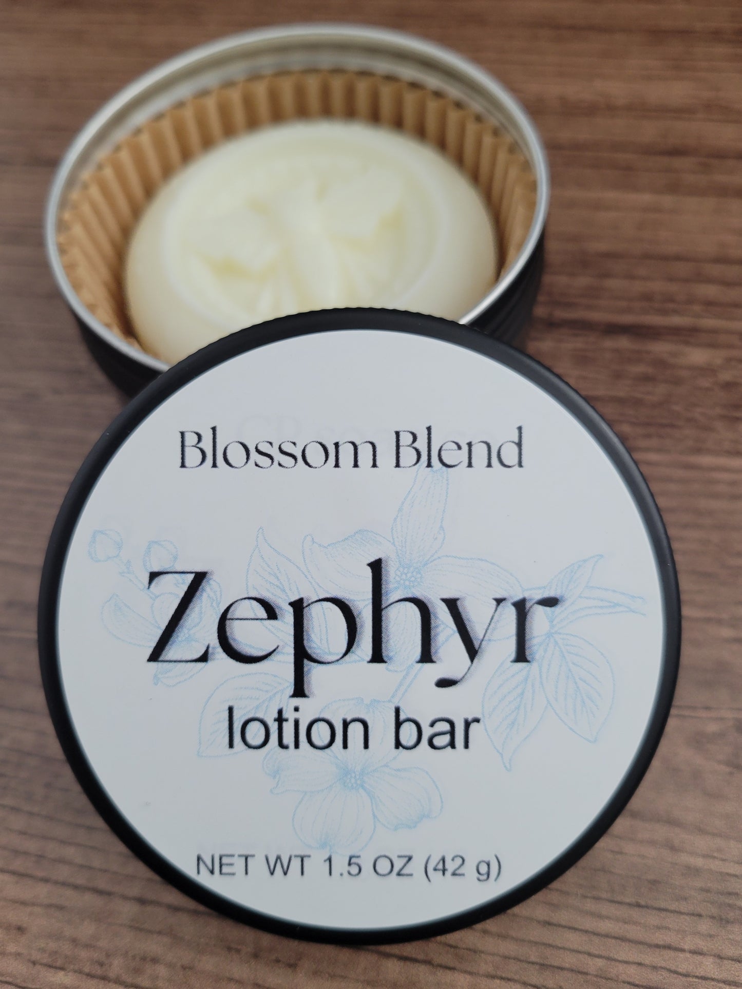 Zephyr lotion bar in a container with 'Blossom Blend' branding on a wooden surface