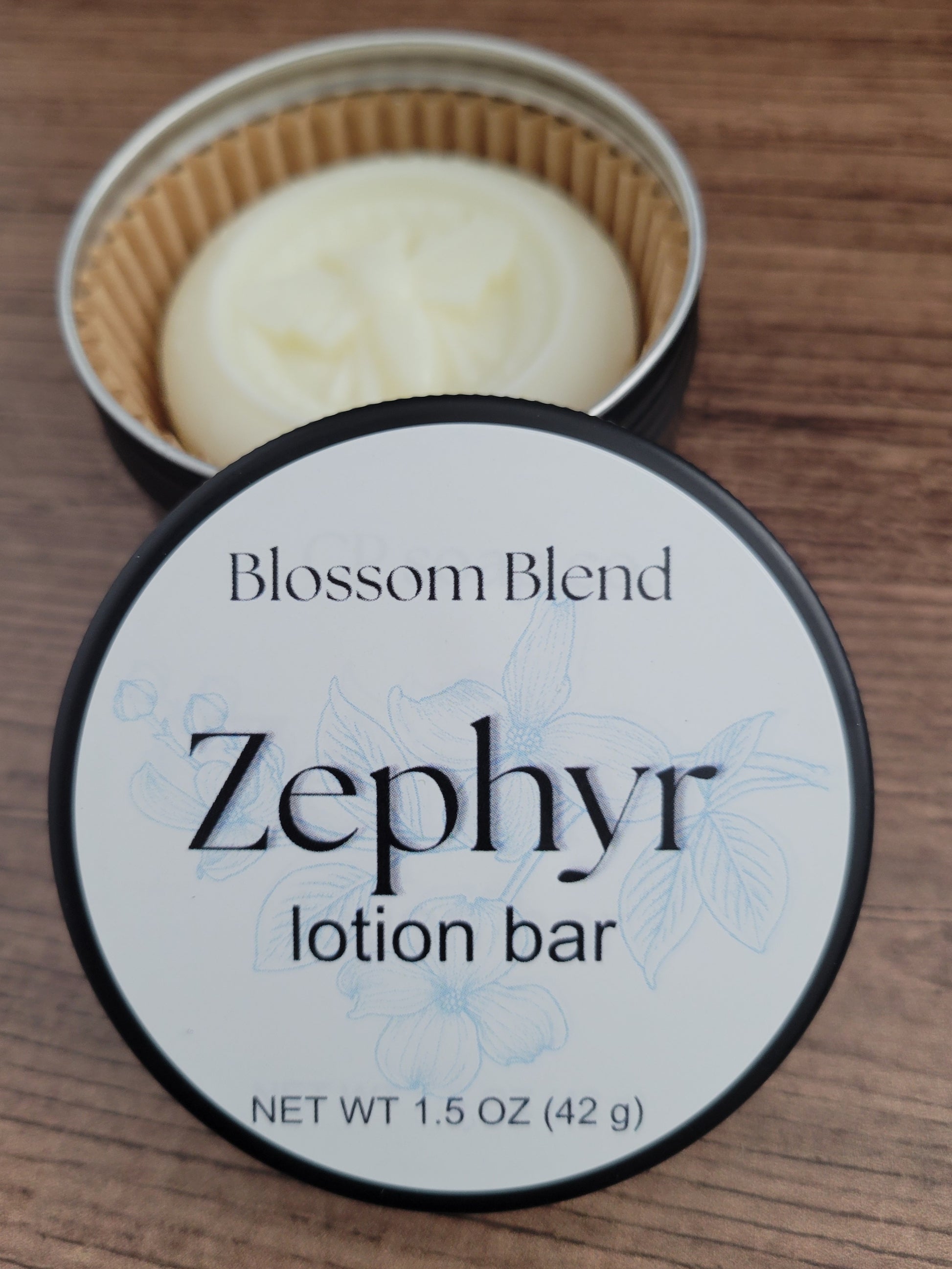 Zephyr lotion bar in a container with 'Blossom Blend' branding on a wooden surface