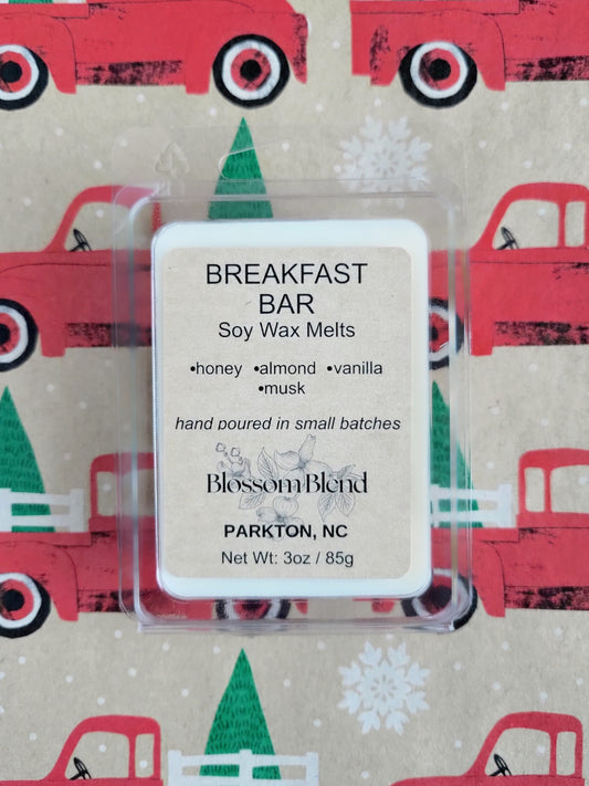 Soy wax melts packaging with 'Breakfast Bar' label on a festive background with red trucks and green trees.