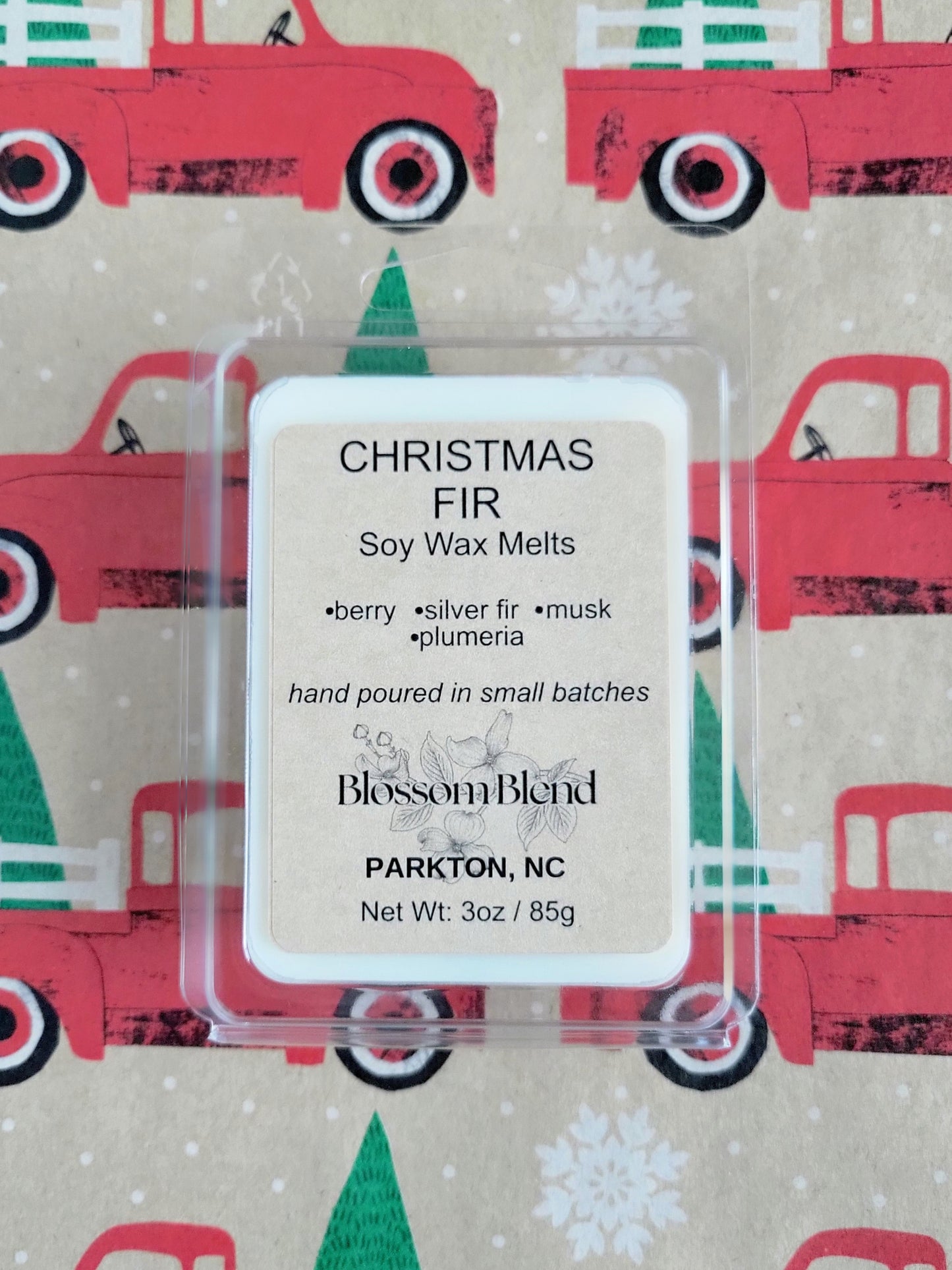 Pack of Christmas Fir soy wax melts with a decorative background featuring red trucks and green trees.