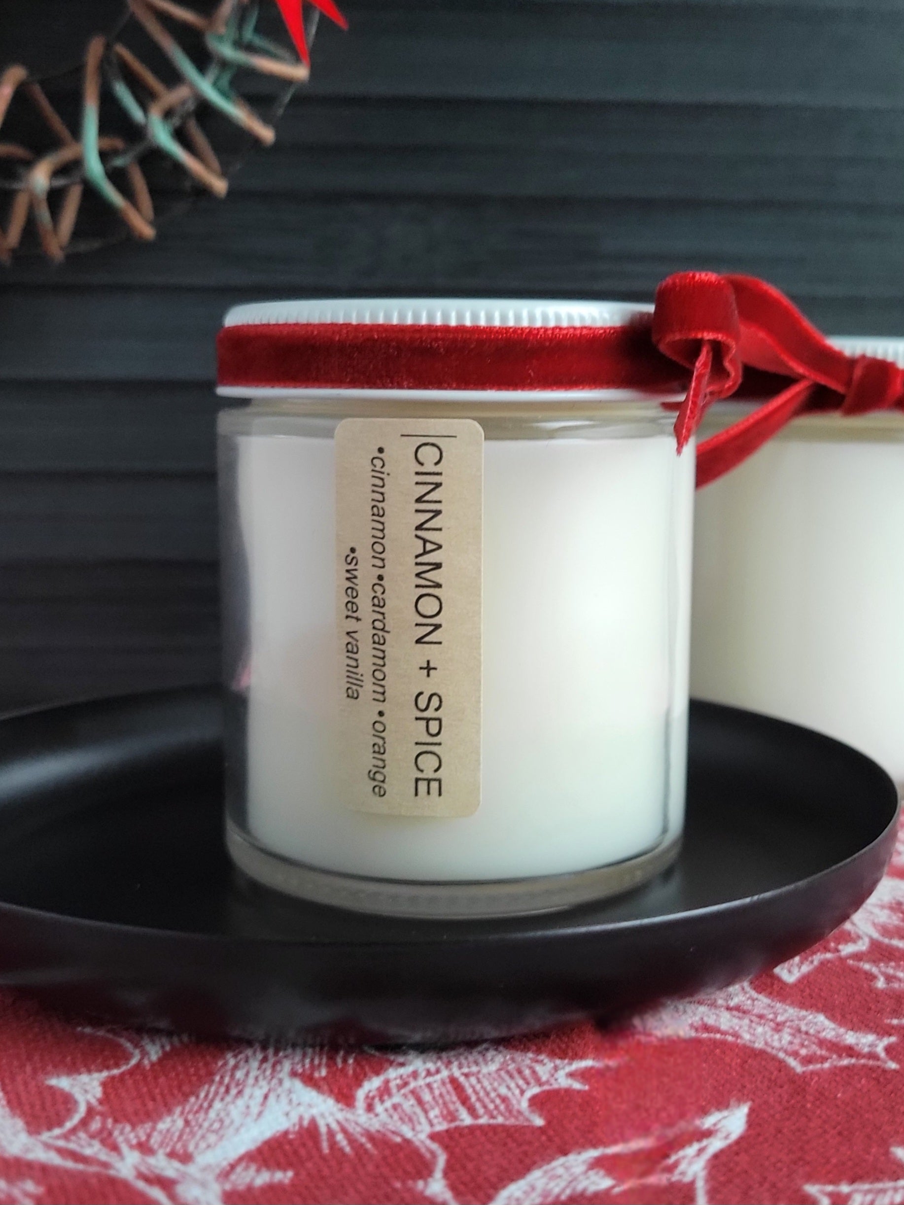 Candle with a red lid and label on a dark surface