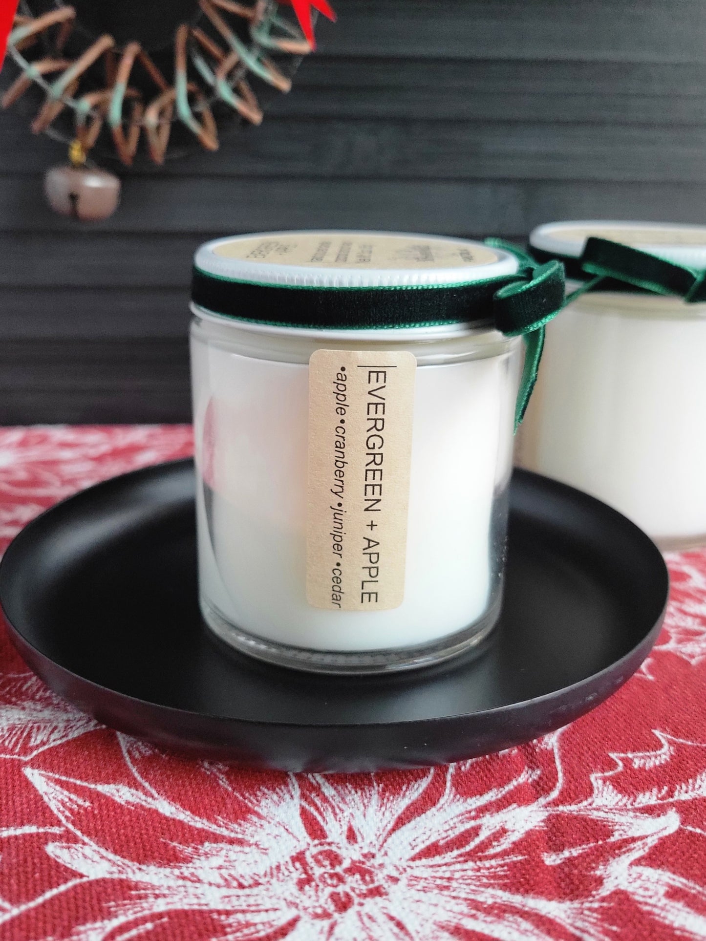 Candle labeled 'Evergreen Apple' on a black plate with a decorative background