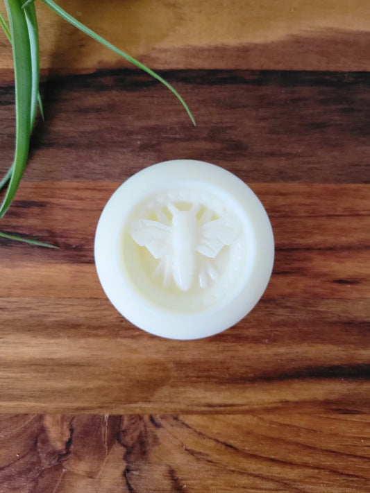 White lotion bar with a bee design on a wooden surface