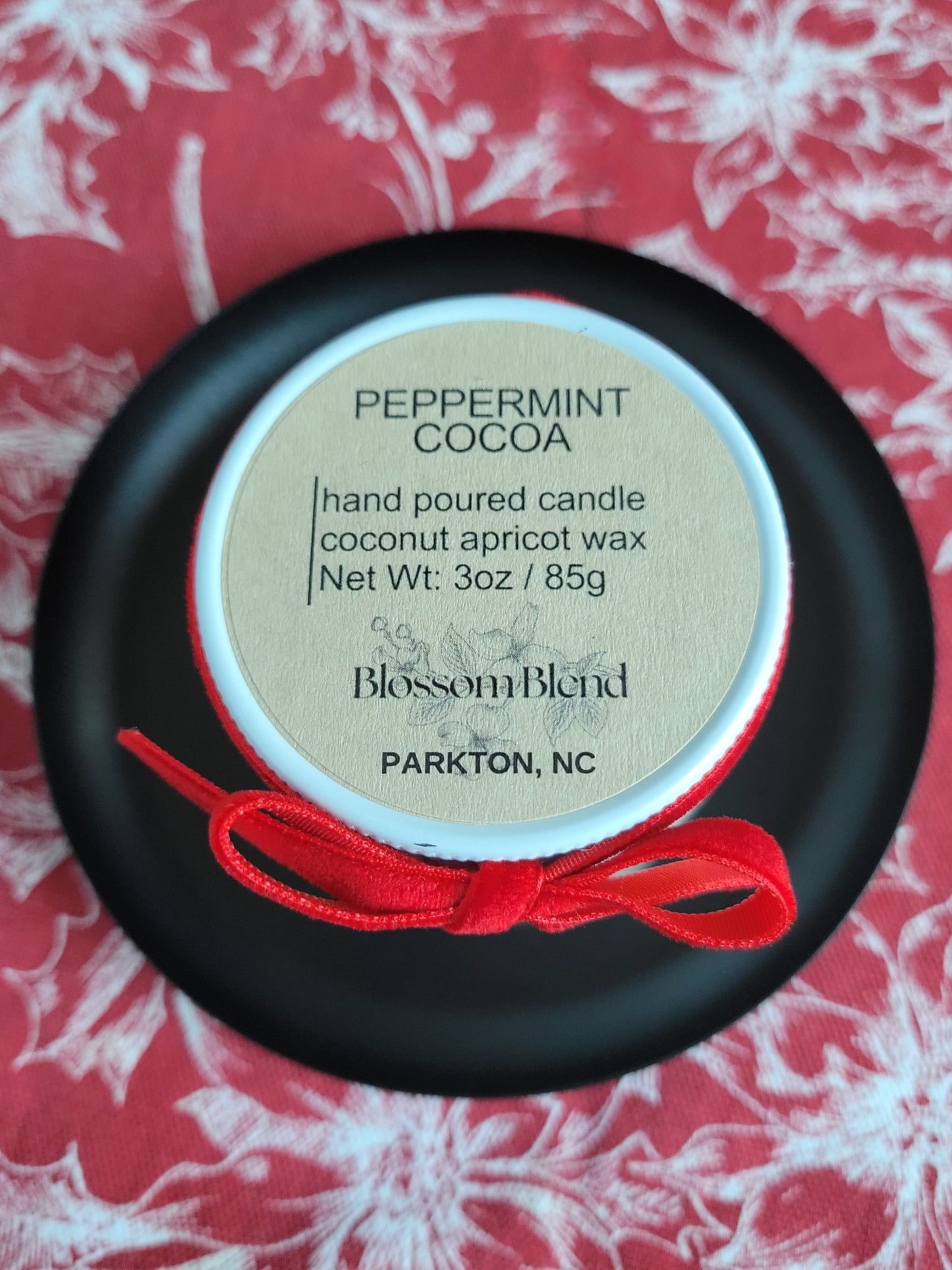 Candle container with 'Peppermint Cocoa' label on a red and white floral background