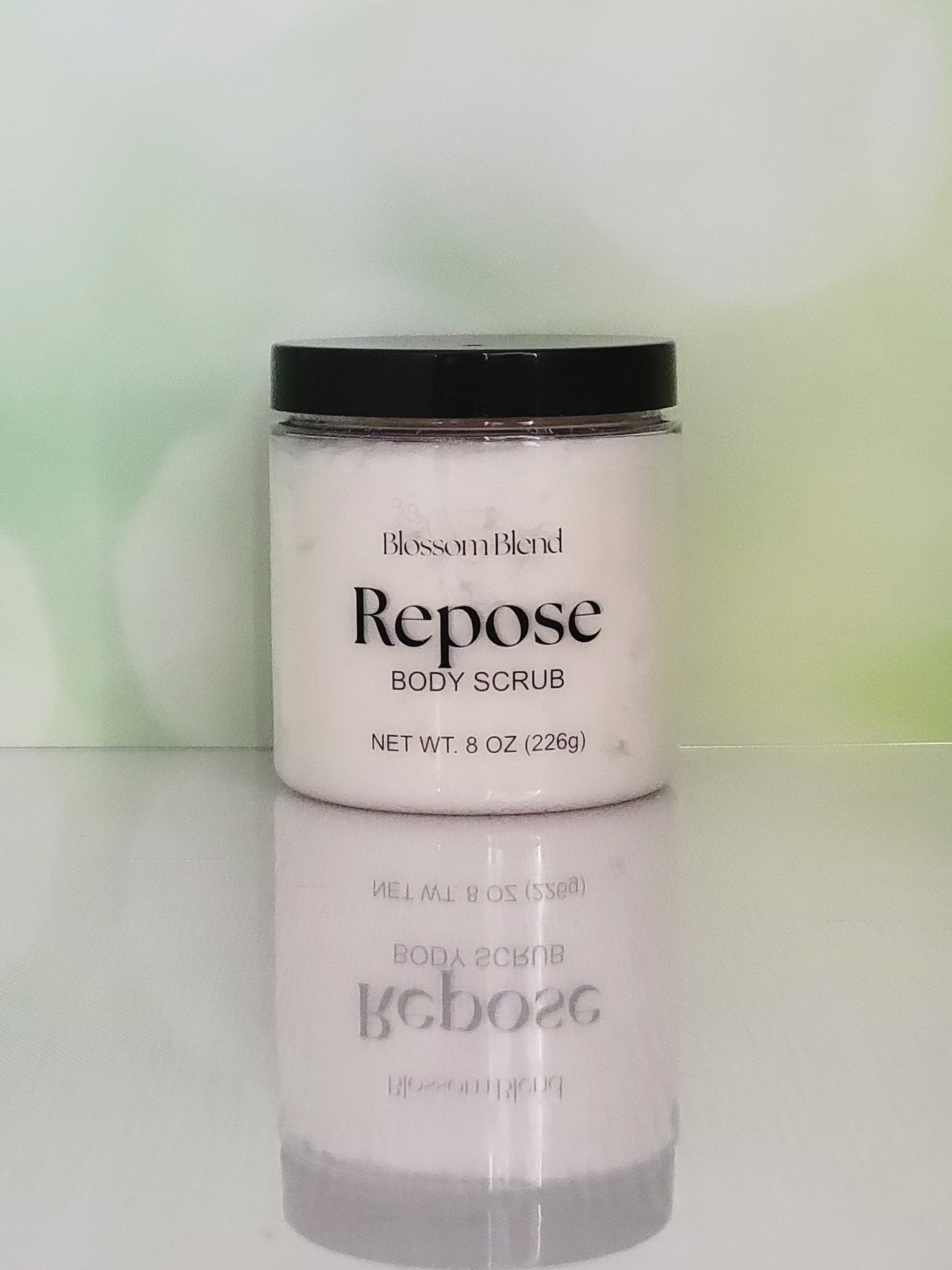 Jar of Blossom Blend Repose Body Scrub on a reflective surface with a blurred green background