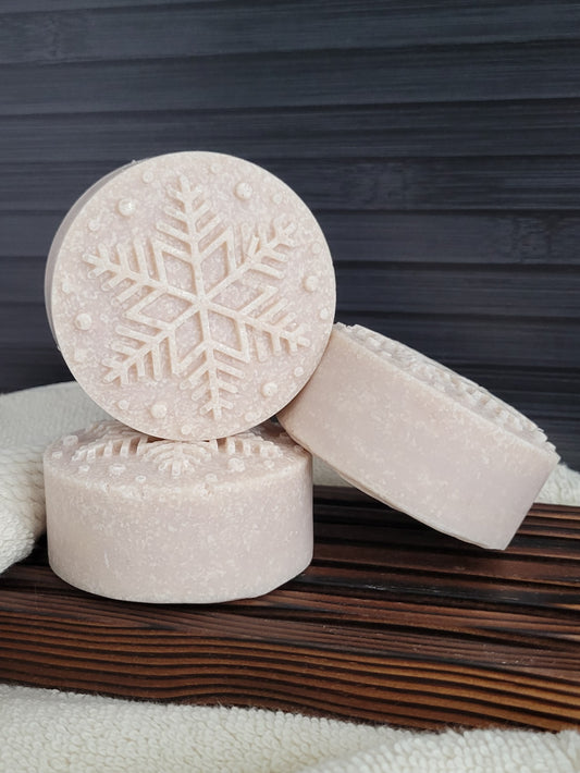 Three soap bars with snowflake design on a wooden surface