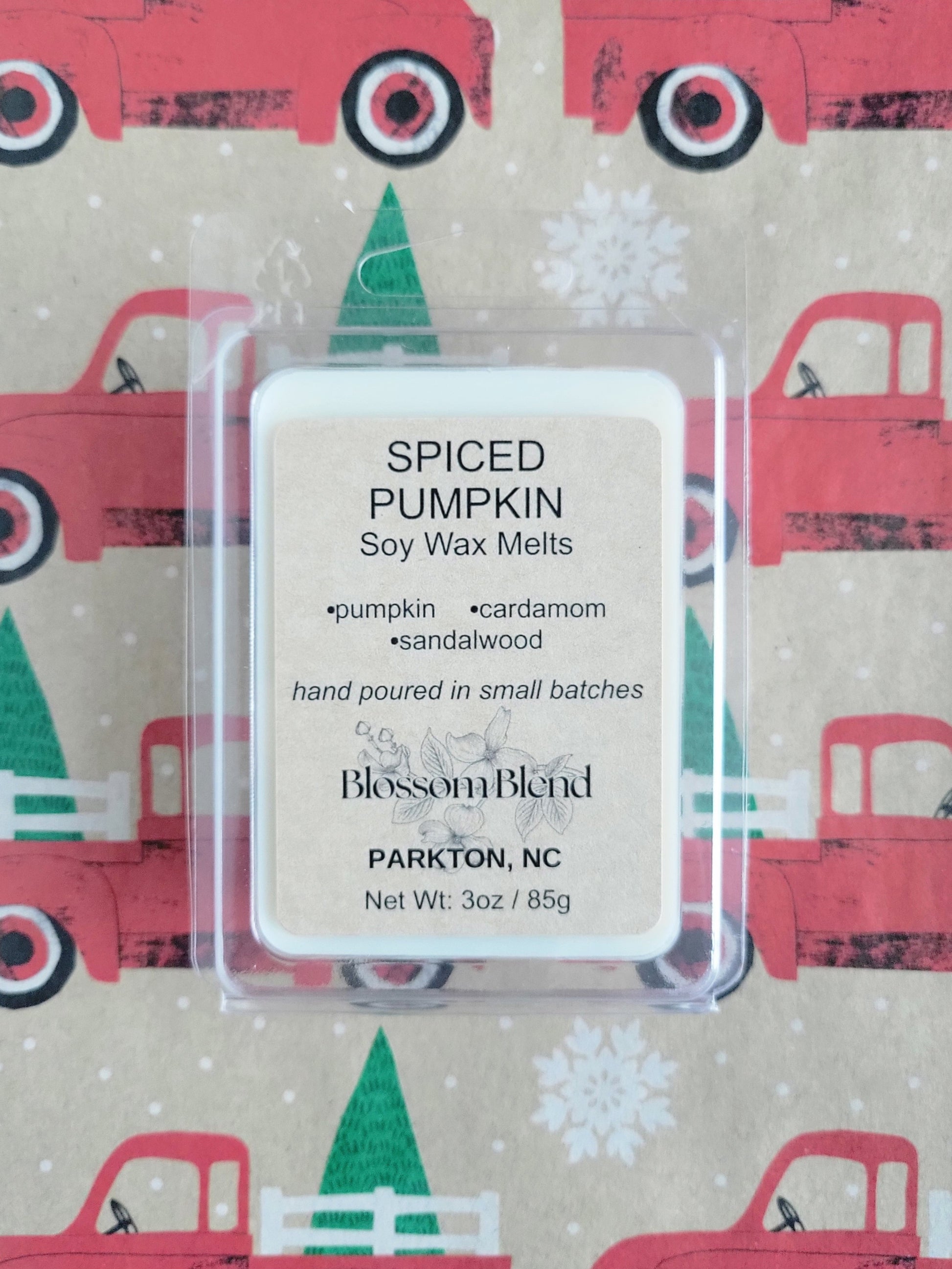 Spiced Pumpkin soy wax melts packaging with a festive background featuring red trucks and green trees.